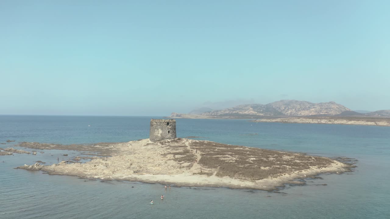 The old tower of Pelosa beach surrounded by blue waters on sunny day
