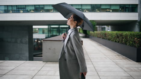 elegant woman walking rainy day holding umbrella. confident businesswoman stroll