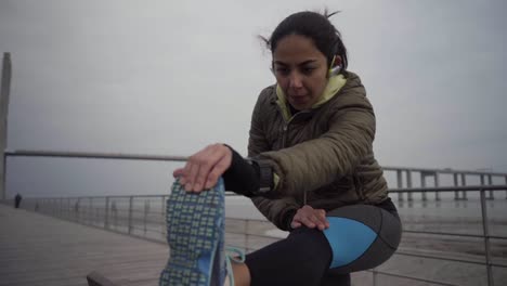 Focused-hindu-sportswoman-stretching-leg-before-workout