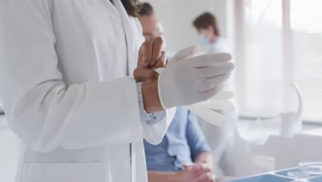 Biracial-female-dentist-with-face-mask-preparing-male-patient-at-modern-dental-clinic