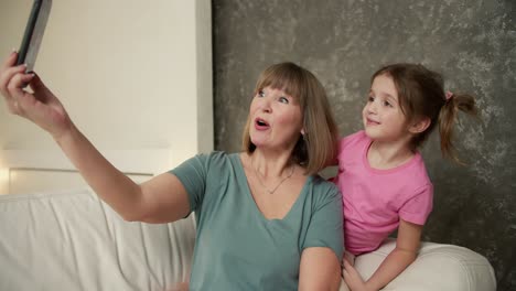 elderly woman use new cool mobile phone, making selfie with her granddaughter