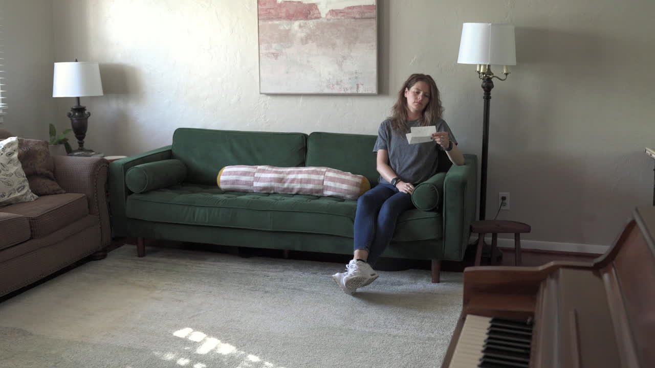 Woman Reading Letter on Green Sofa in Living Room