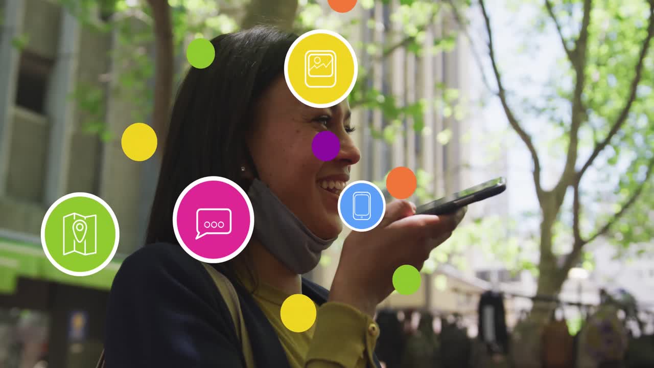 animación de icono en círculos sobre feliz mujer biracial hablando en altavoz en teléfono celular en la calle