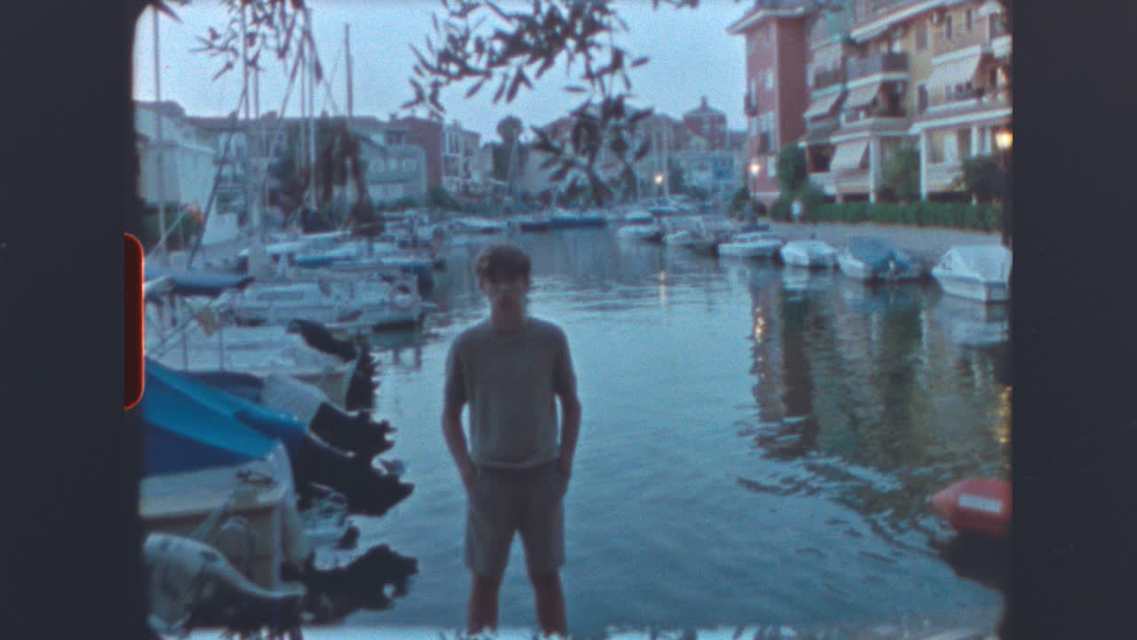 Young Man Standing by a Marina at Dusk with Vintage Film Aesthetic