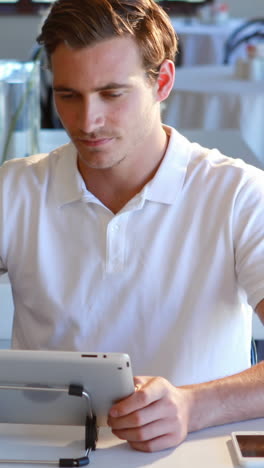 man having cup of coffee and using digital tablet