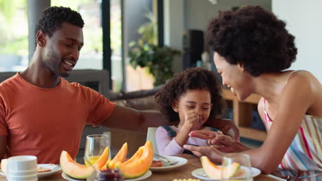 Foto-Familiar-Con-Padres-E-Hija-En-Casa-Jugando-En-La-Mesa-Antes-De-Desayunar