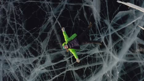 una chica yace en el hielo en invierno con ropa cálida y agita sus brazos y piernas
