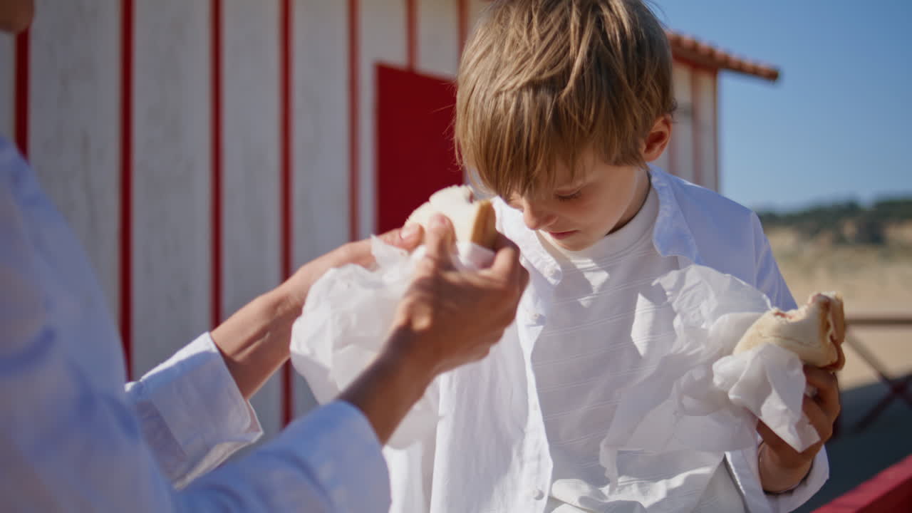 Mother child eating sandwiches at sunny beach closeup. Smiling mom son enjoying