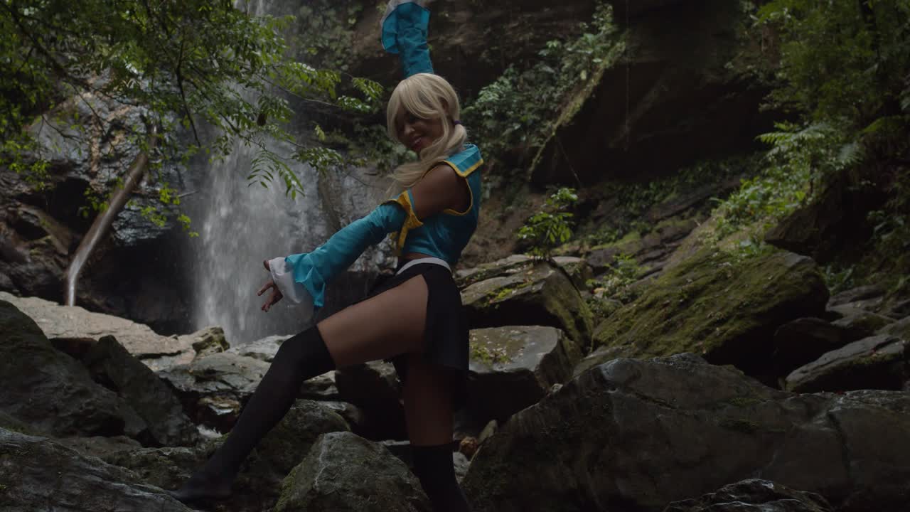 lucy heartfilia anime cosplayer disfrutando de la naturaleza con una increíble cascada en el fondo
