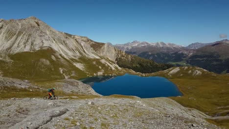 un ciclista con ropa colorida recorre el camino hacia el lago rims, toma aérea constante