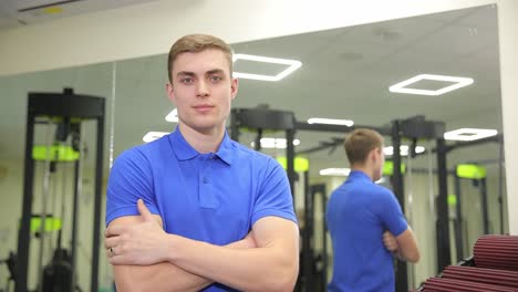 a man in an electric blue shirt stands in the gym with arms crossed a man in an electric blue shirt is standing in a gym his arms crossed in a gesture of confidence he looks around the room with a smile sharing the energy of the event