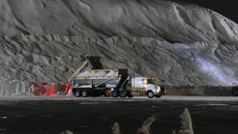 Trucks-Unload-Snow-at-the-Snow-Dumping-Station-After-Clearing-the-Streets-at-Night-in-Winter---Montreal,-Canada---Static-Medium-Shot