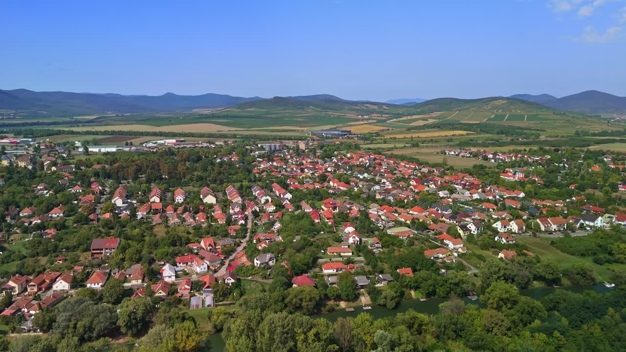 Orbital aerial view of the suburban area of Sárospatak with family houses and the Zemplén Mountains on a sunny autumn day in Hungary