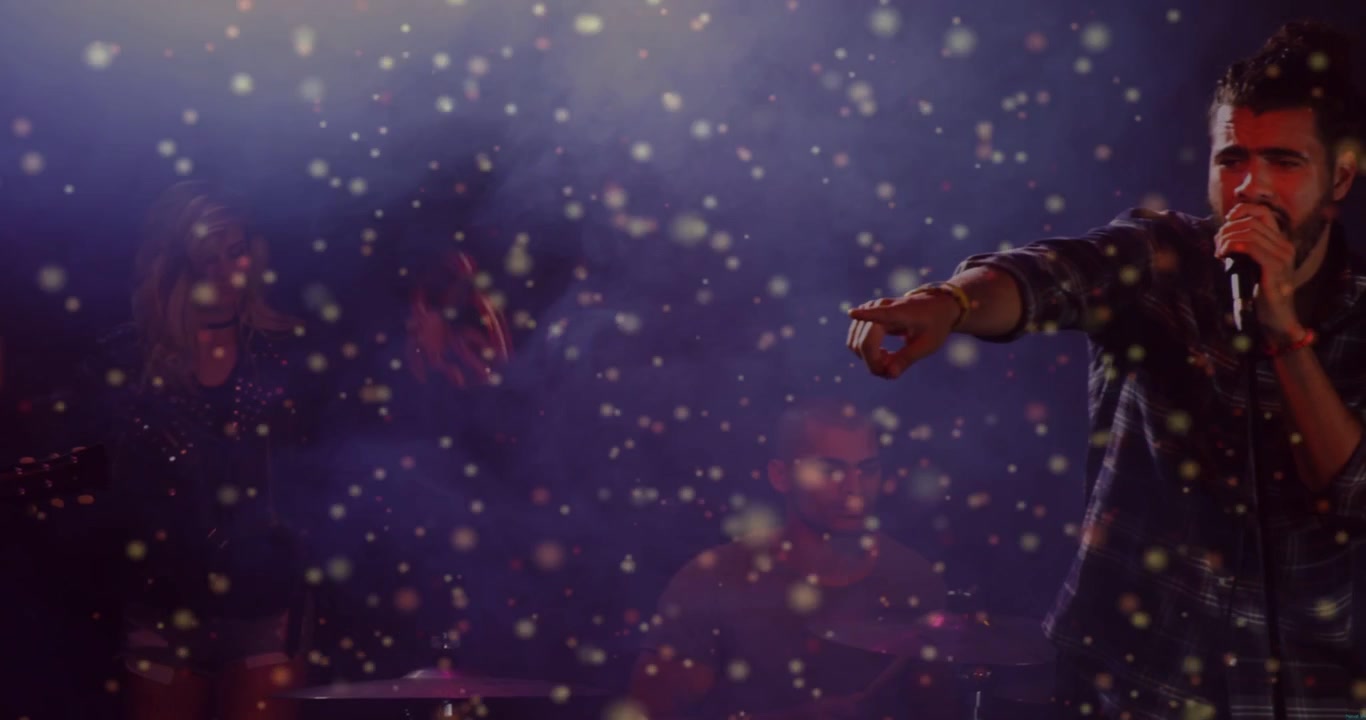 Vertical video: Lead singer entering right, raising mic, connecting crowd amid concert particles