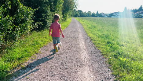 Erleben-Sie-Die-Freude-Der-Kindheit-Im-Herzen-Der-Deutschen-Landschaft,-Wenn-Ein-Kleiner-Junge-Leidenschaftlich-Einen-Fußball-über-Ein-Malerisches-Feld-Spielt