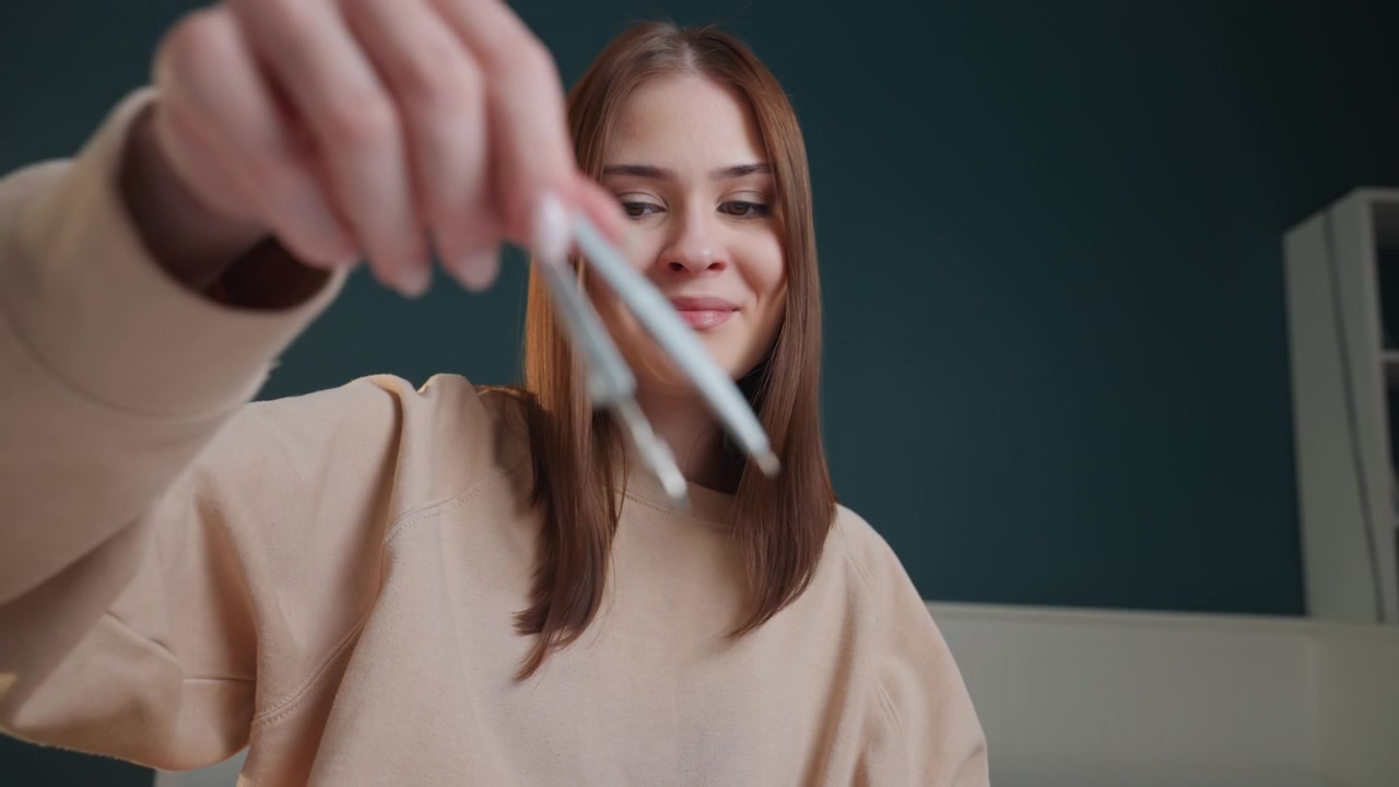 Joven tutora en un escritorio, ambiente hogareño acogedor, mujer morena con suéter corrigiendo gramática con un bolígrafo verde, expresión concentrada y mano firme, perspectiva de primer plano mostrando escritura y corrección, en línea.
