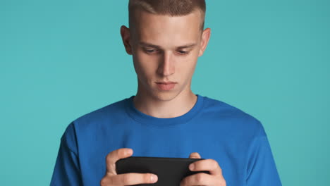 young blond guy playing with his smartphone