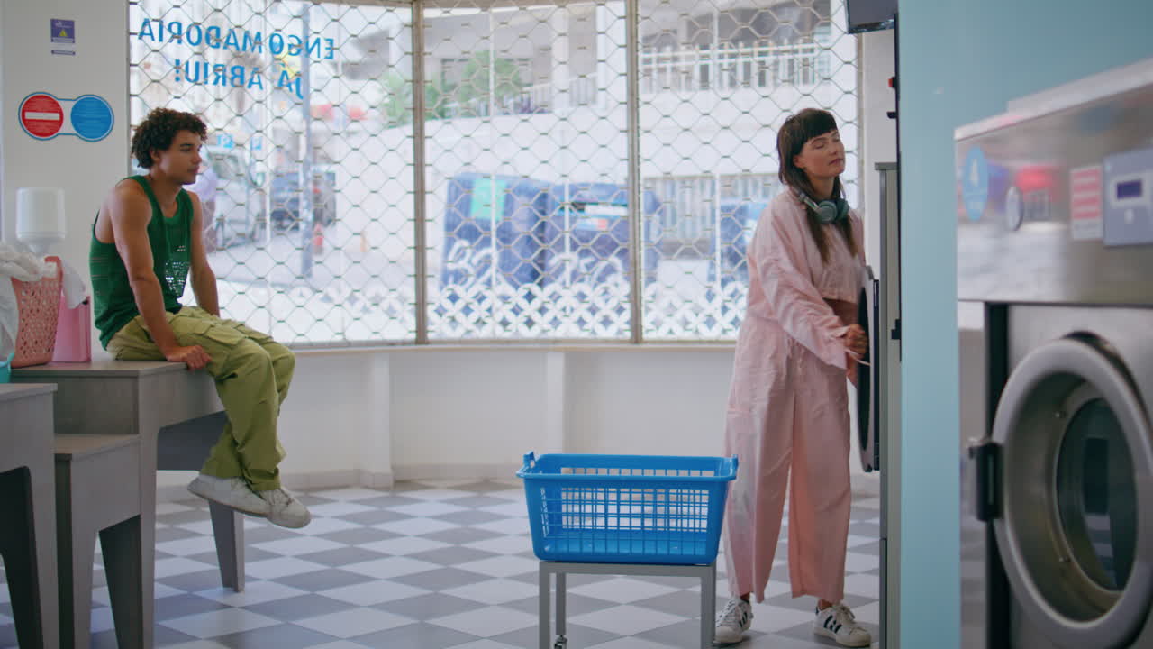 젊은이들이 옷을 세탁하는 자가 서비스. 예쁜 소녀는 깨한 색을 꺼내