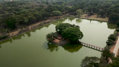 aerial view of a serene pond with a red bridge leading to a lush island