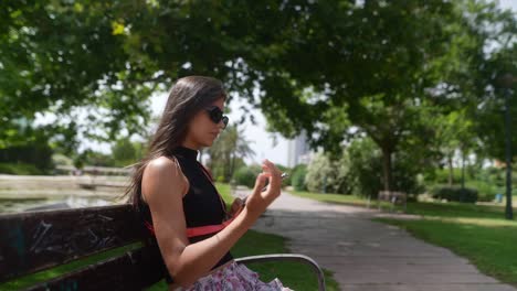 young woman sitting in a park using her phone