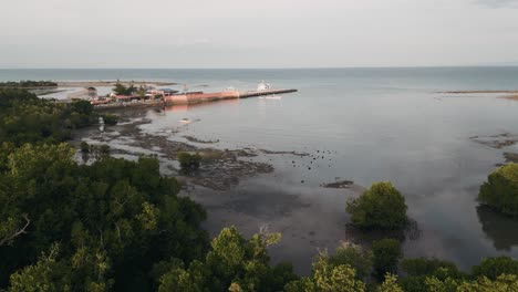 dramatic aerial overview of taloot argao port at sunrise, showing the bustling maritime activity in cebu, philippines, tilt up with clouds reflecting in water