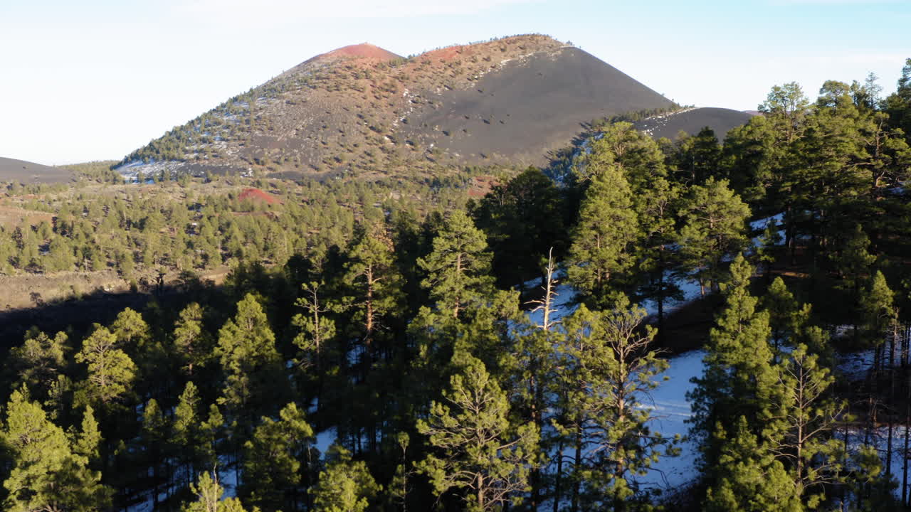 아리조나 주 국립 기념물에 있는 일몰 분화구 화산 위의 나무와 부족한 농장을 통해 날아가는 무인 항공기
