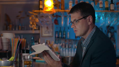 man having drink and working with pad in the bar