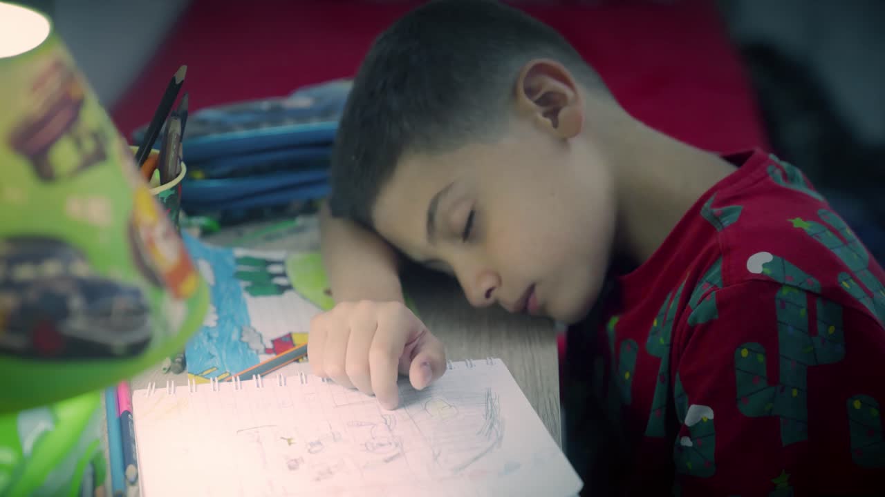 bambino stanco fa i compiti a casa di notte e dorme sulla scrivania