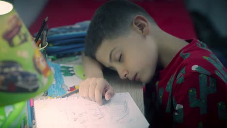niño cansado hace la tarea por la noche y duerme en el escritorio