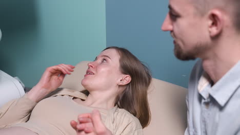 pregnant woman having ultrasound scan at the gynecologist office while loving husband holding her hand 3