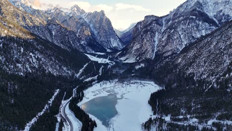 frozen lake in the italian dolomites surrounded by mountains during winter season (drone footage)