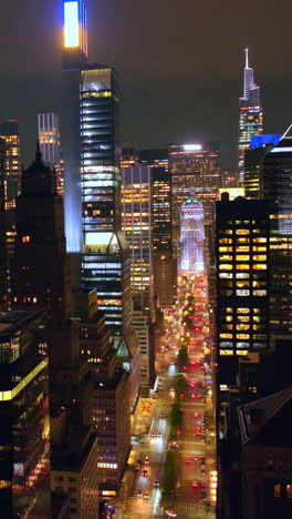 amazing skyscrapers with lights on. drone rising over glamorous buildings at night. cloudy sky background. vertical video