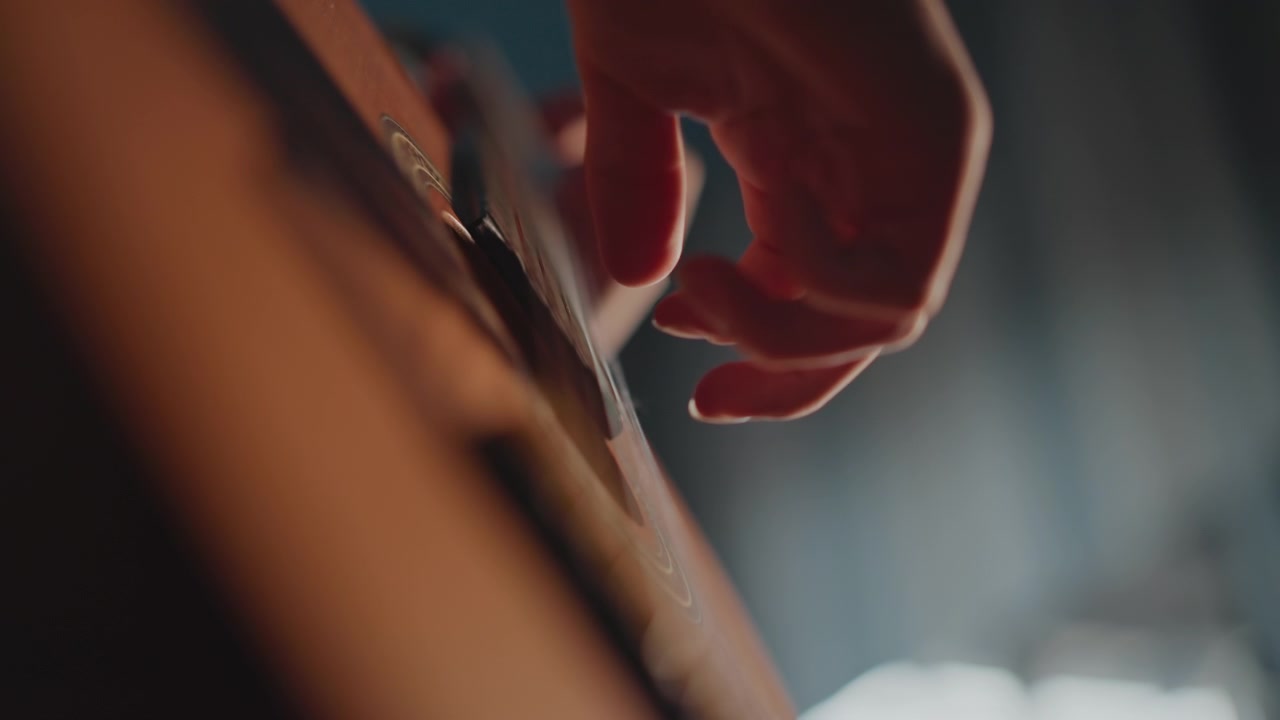 Primo piano di un insegnante di chitarra con corde di nylon che guida la tecnica in una sala prove poco illuminata, l'istruttore forma accordi e arpeggi con enfasi sul tempo e sulle dinamiche, atmosfera di coaching motivante con mano precisa
