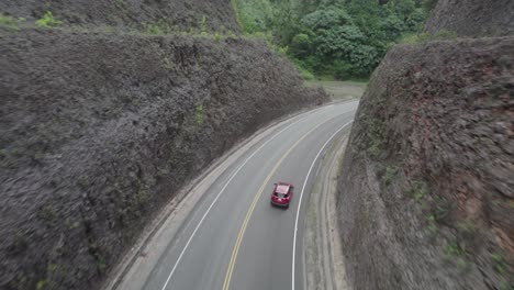 Seguimiento-Aéreo-De-Un-Automóvil-Rojo-Conduciendo-Por-Una-Carretera-De-Montaña-Cortada,-Las-Terrenas,-República-Dominicana