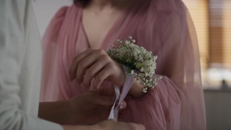 unrecognizable  woman applying flower corsage on girl's wrist before prom