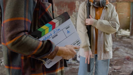 the camera focus on to the hands of an production worker as he holds a clapperboard