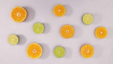 slices of fresh oranges and limes rotate in circle on silver theme. stop motion