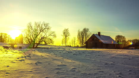 Sunset-in-winter-wonderland-with-log-cabin-covered-in-snow-in-Latvia,-time-lapse