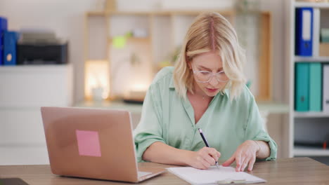 woman works on laptop and takes notes during training