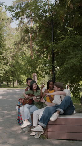 friends playing guitar and singing together in a park