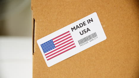 hands applying made in usa flag label on a shipping cardboard box with products