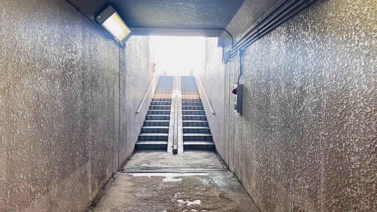 A slow forward camera movement through a concrete tunnel toward stairs in Kanazawa, Japan