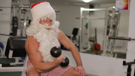 santa claus with dumbbells in the gym, strong santa is preparing for the winter holidays