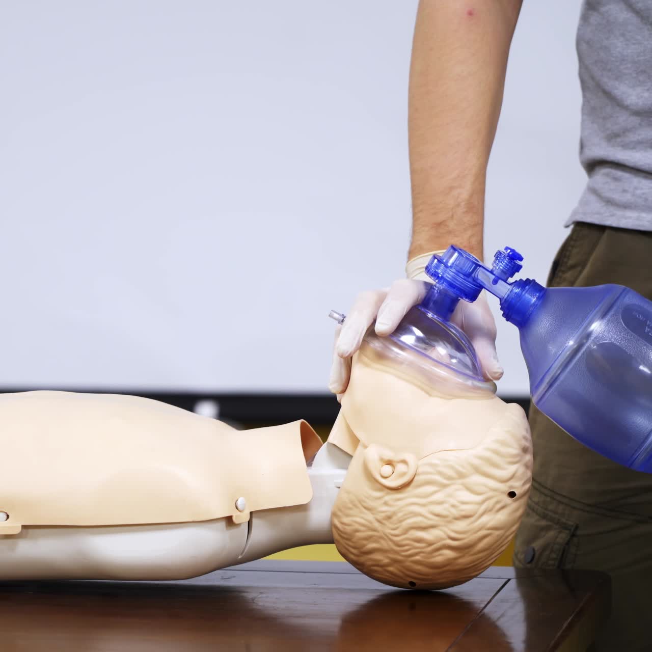 Training in medical center. Person in protective gloves giving breath exercise on a dummy. Education on a mannequin for giving first aid