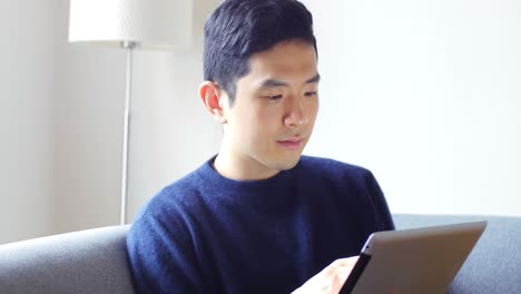 man using digital tablet on sofa in living room 4k