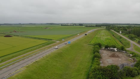 toma aérea de tráfico en una carretera a través de tierras agrícolas en la península de walcheren en zelanda, los países bajos en un día nublado de verano