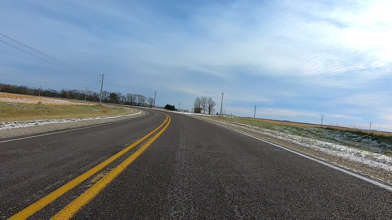 Point of View out of the drivers window; Driving on highway past farms, cows, truck and fields in rural Illinois USA on snow and ice.