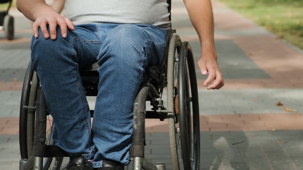 Man with disabilities in wheelchair walk at the park alley