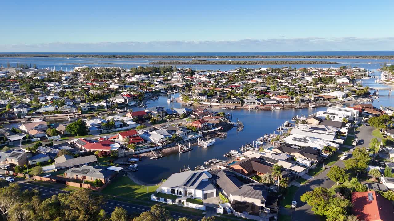 Drone footage captures luxury homes and waterways in Gold Coast, Australia, under clear skies with vibrant colors and serene atmosphere