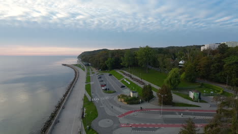 amanecer sobre el bulevar costero en gdynia, cielo ligeramente nublado, transeúntes individuales paseando por el paseo marítimo